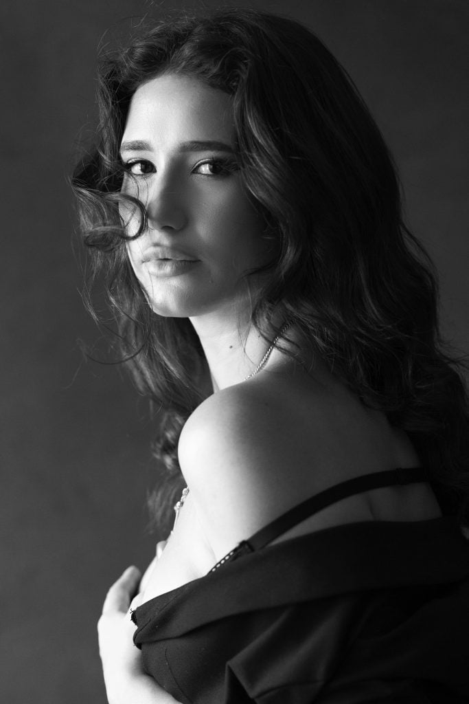 Black and white portrait of a woman with flying hair, smiling in a cinematic pose. Photographed by a professional photographer in Luxembourg.