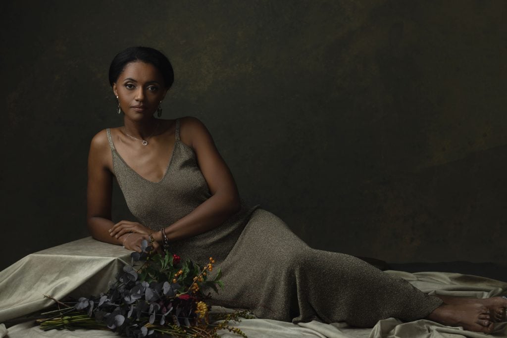 Elegant woman reclining in a shimmering gold dress in a painterly fine art portrait. Photographed by a professional photographer in Luxembourg.