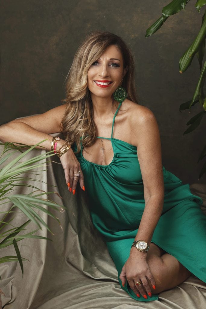 Stylish woman in green dress with golden accessories smiling brightly