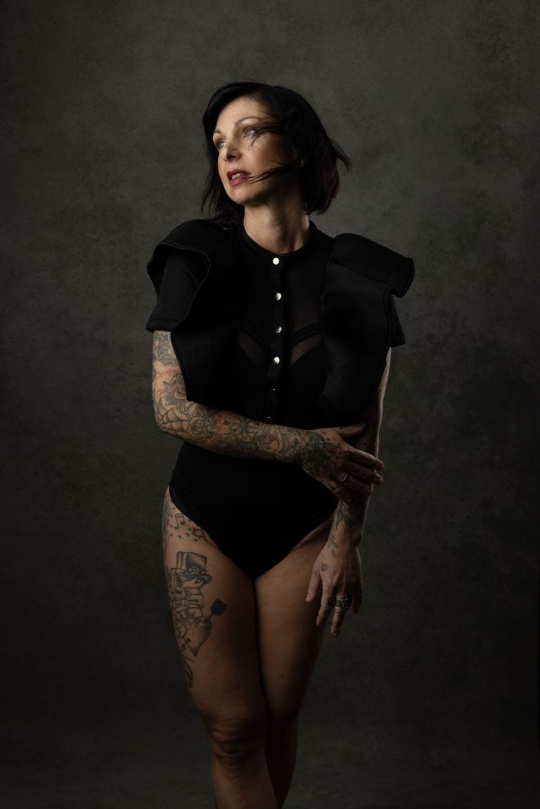 Expressive portrait of a tattooed woman in a black bodysuit captured for the Over 40 campaign by Massen Photography. Photographed by a professional photographer in Luxembourg.