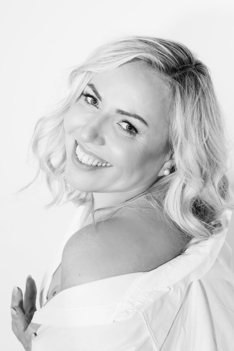 Black and white high-key portrait of Diana smiling over her shoulder