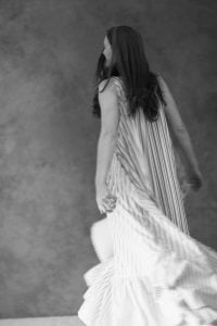 Blurred motion shot of a woman twirling in a flowing striped dress