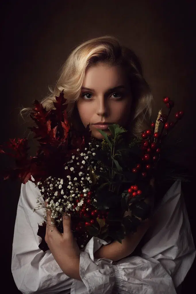 Soulful portrait of a woman in white shirt holding a bouquet of autumn leaves and winter berries, Luxembourg photography.
