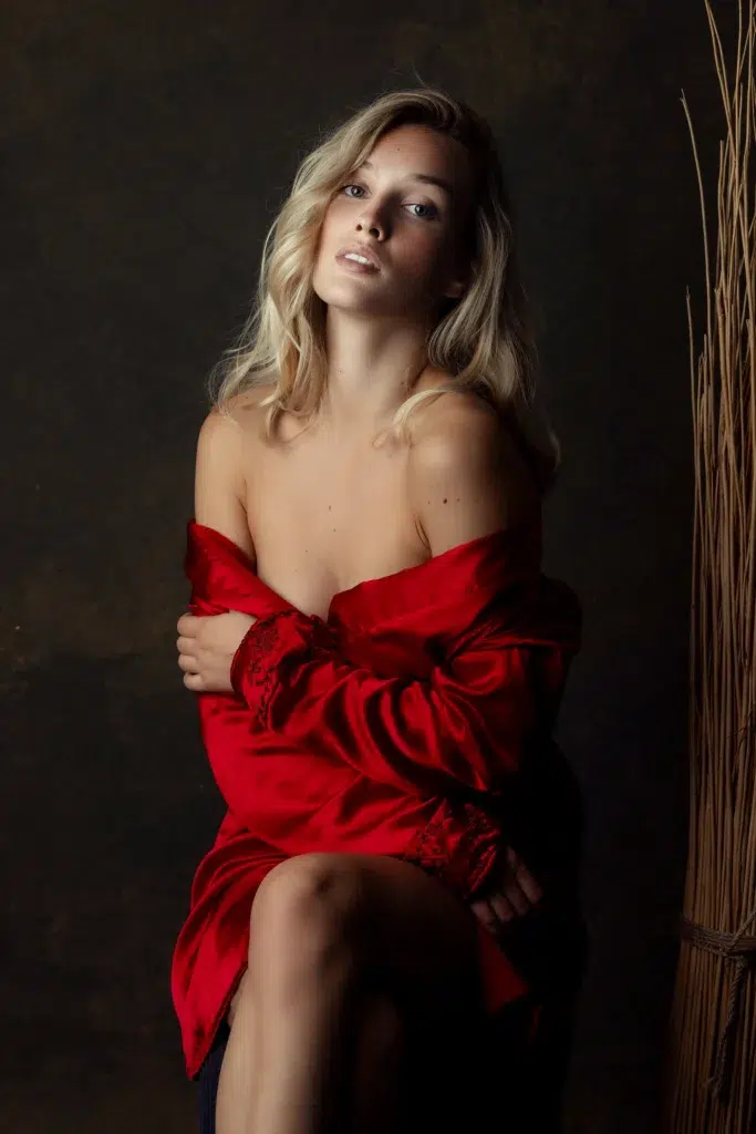 Boudoir portrait of a woman in a red silk robe in a warm studio setting, Massen Photography Luxembourg