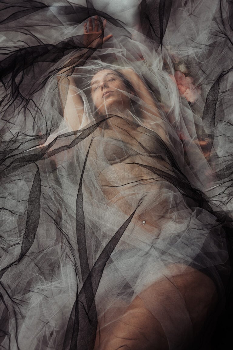 Artistic boudoir portrait of a woman wrapped in black and white tulle with soft floral accents, Massen Photography Luxembourg
