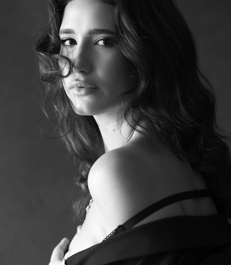 Black and white portrait of a woman with flying hair, smiling in a cinematic pose. Photographed by a professional photographer in Luxembourg.