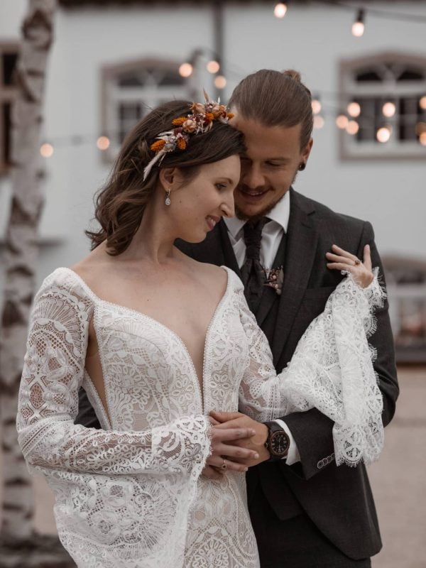Bride and groom embracing under romantic string lights