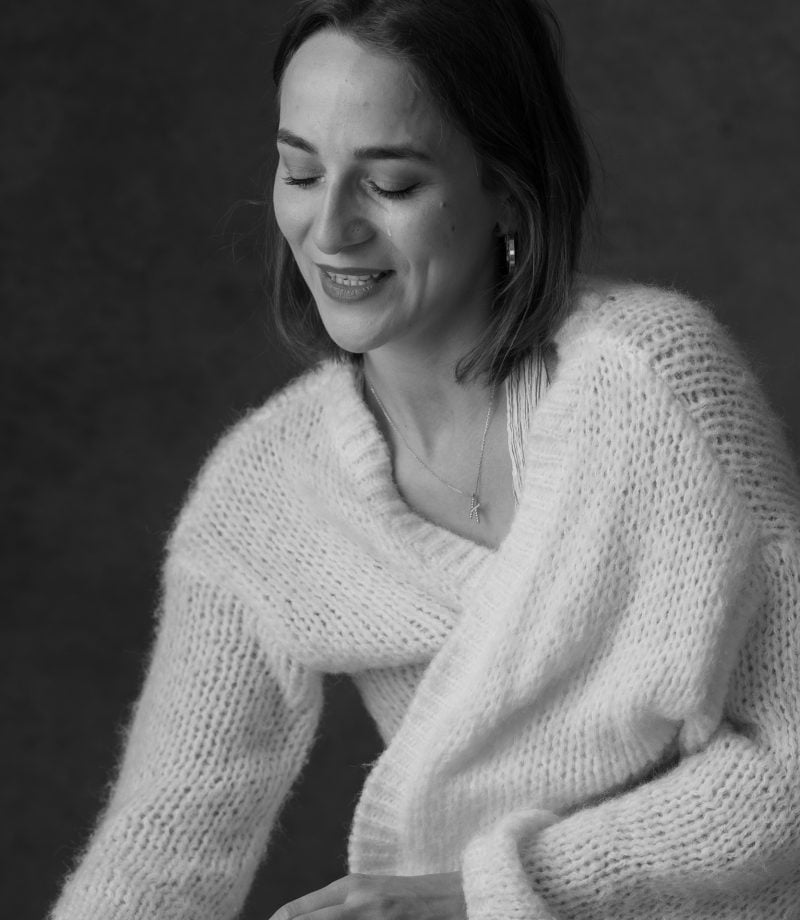 Laughing woman in a soft knitted cardigan, eyes closed in a natural moment